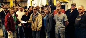 Michele Hardin (front, left) accepts a check from the fabrication department at Scranton Manufacturing to purchase books for the Ram Readers program.