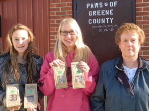 PAWS volunteer Cheryl Swanson (right) accepts dog treats from 4-H dog project youth superintendents Noelle Gray (left) and Ashley Kuhl.
