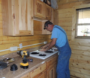 Electrician Chris Durlam installs the stove top on Tuesday.