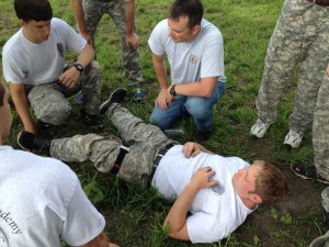 Brett Cranston (center, kneeling) teaches combat first aid