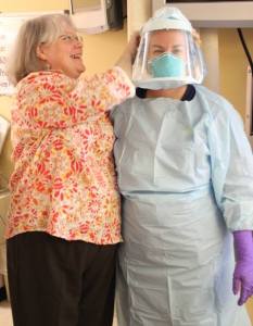 Sandy Atkinson helps nurse Heather Kinsey don a protective hood