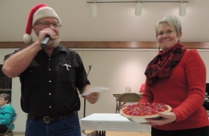 Angie Jewett shows a pie she made as Dale Higgins coaxes bids