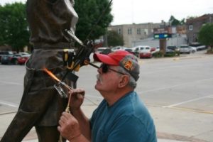Dan Benitz reattaching an arrow broken from the Doreen Wilber statue by young vandals last month